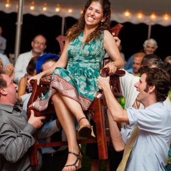 Sister of bar mitzvah boy lifted on a chair during- the hora