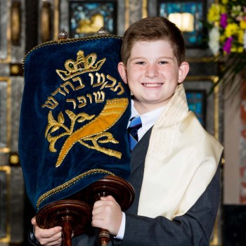 Bar mitzvah boy proudly hoists the Torah