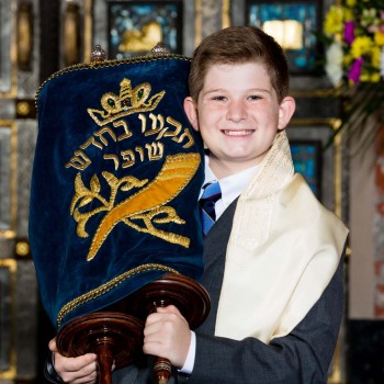 Bar mitzvah boy proudly hoists the Torah