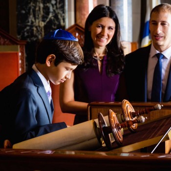 Parents look on as boy reads Torah