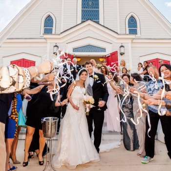 Bride and groom exit the chapel as guests throw rice and confetti