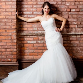 Bridal portrait in mermaid dress in front of brick wall