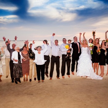 Wedding party jumping for joy on beach