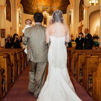 Father and son of the bride escort her up the aisle
