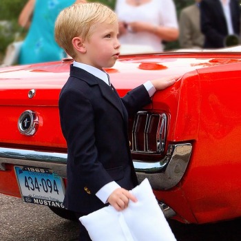 The ring bearer and a red Ford Mustang